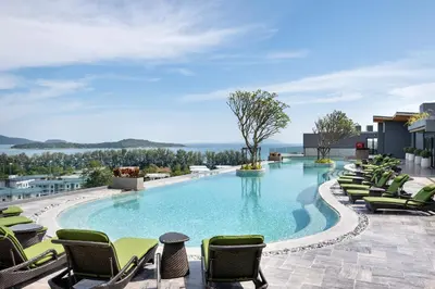a large swimming pool with lounge chairs on a building at Calypso Garden by Villacarte in Rawai Beach