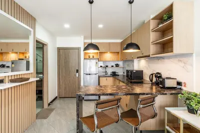 a kitchen with wooden cabinets and a counter with chairs at Calypso Garden by Villacarte in Rawai Beach