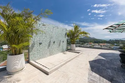 a patio with palm trees and a wall at Calypso Garden by Villacarte in Rawai Beach