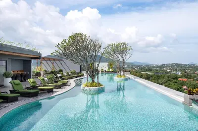 a large swimming pool with chairs and trees on a building at Calypso Garden by Villacarte in Rawai Beach
