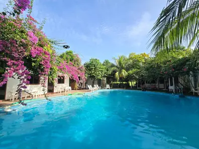 a large swimming pool with blue water and flowers at OASIS Phuket Airport in Nai Yang Beach