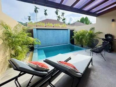 a patio with a swimming pool and two chairs at Beautiful 1br Plunge Pool Villa Walk To Bangtao Beach in Ban Thalat Choeng Thale