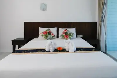 a bed with two white towels and flowers on it at Kiwi Boutique Hotel in Patong Beach
