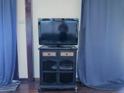a tv sitting on a stand in a room with blue curtains at Lam Sai village hotel Koh Yao Noi in Ko Yao Noi