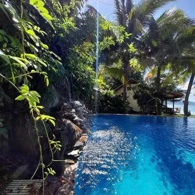 a pool with a waterfall next to a house at Lam Sai village hotel Koh Yao Noi in Ko Yao Noi