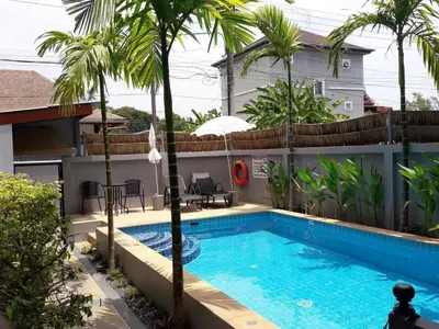 a swimming pool in front of a house with palm trees at Vivi Boutique Room Hotel SHA Plus in Rawai Beach