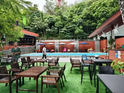a woman standing in front of a pool with tables and chairs at Holiday Resort - SHA Plus in Ko Yao Noi