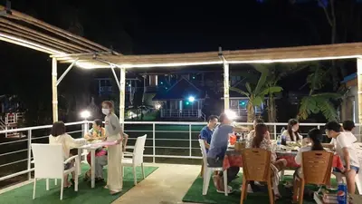 a group of people sitting at tables on a deck at night at Holiday Resort - SHA Plus in Ko Yao Noi