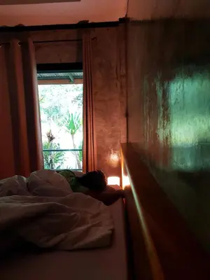 a person laying on a bed in front of a window at Annie Meen's place Koh Yao Noi in Ko Yao Noi