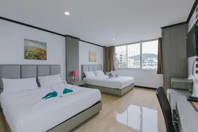 a hotel room with two beds and a television at Royal Beach Residence, Patong Beach in Patong Beach