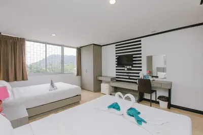 a hotel room with two beds and a desk at Royal Beach Residence, Patong Beach in Patong Beach