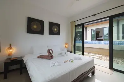 a bedroom with a bed and a view of a pool at Foxtail Palm Villa in Rawai Beach