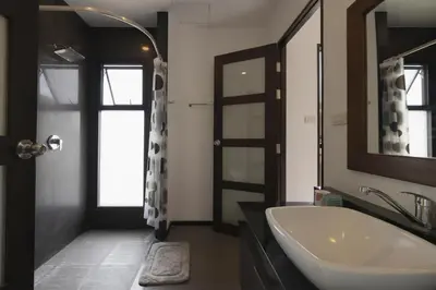 a bathroom with a white sink and a mirror at Cocktail Palm Villa in Rawai Beach