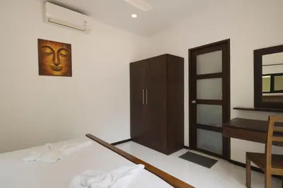 a room with a bed and a cabinet and a mirror at Cocktail Palm Villa in Rawai Beach