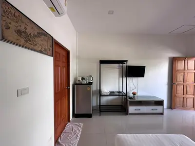 a room with a refrigerator and a table in it at นิวเวฟภูเก็ต in Ban Na Kok