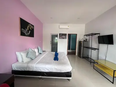 a bedroom with a large bed with a purple wall at นิวเวฟภูเก็ต in Ban Na Kok