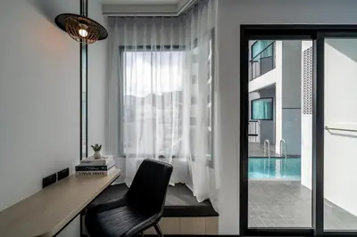 a desk and a chair in a room with a pool at Ratri Hotel Phuket Old Town in Phuket Town