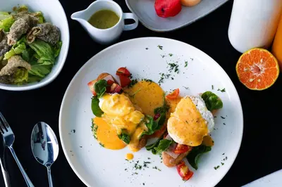 a plate of food with eggs and vegetables on a table at Ratri Hotel Phuket Old Town in Phuket Town
