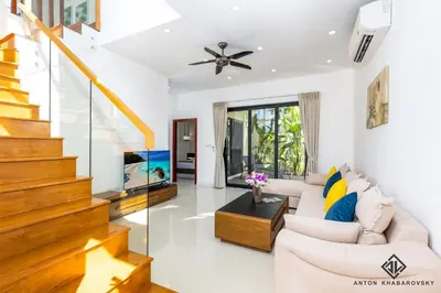 a living room with a white couch and stairs at Hideaway Lake Villas By Cozy Lake in Bang Tao Beach