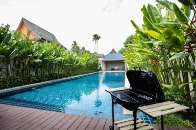 a resort swimming pool with a chair next to it at Hideaway Lake Villas By Cozy Lake in Bang Tao Beach
