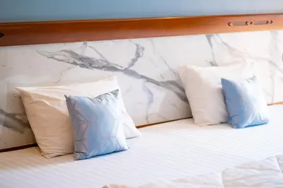 two pillows on a bed with a marble wall at Mayfa Hotel - SHA extra plus in Phuket Town