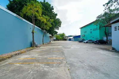 an empty street with a blue building and trees at Mayfa Hotel - SHA extra plus in Phuket Town
