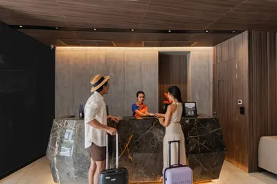 a man and woman standing at a counter with luggage at Citrus Patong Hotel by Compass Hospitality in Patong Beach