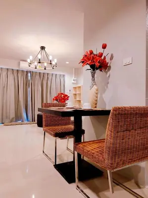 a dining room with a table with chairs and a vase of flowers at The Nakara Town in Ban Rangeng