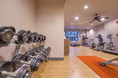 a gym with rows of dumbbells in a room at Zenmaya Oceanfront Phuket, Trademark Collection by Wyndham in Patong Beach