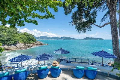 a group of blue chairs and umbrellas on a beach at Zenmaya Oceanfront Phuket, Trademark Collection by Wyndham in Patong Beach