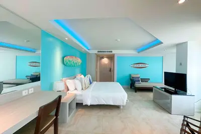 a bedroom with blue walls and a bed and a television at Zenmaya Oceanfront Phuket, Trademark Collection by Wyndham in Patong Beach