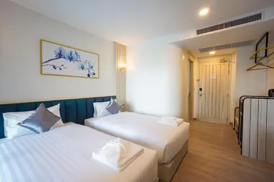 a hotel room with two beds and a hallway at Poolrada Boutique Hotel - SHA Plus in Thalang