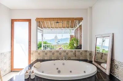 a bath tub in a room with a large window at Soul Villas - Beachfront Private Pool Villas, Phuket Nature Retreat in Panwa Beach