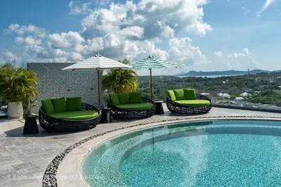 a swimming pool with chairs and umbrellas on a patio at 2-Bedroom Apartment at Calypso Garden Residences in Rawai Beach