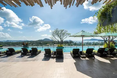 a pool with chairs and umbrellas on a patio at 2-Bedroom Apartment at Calypso Garden Residences in Rawai Beach