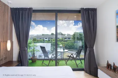 a bedroom with a large window with chairs and a table at 2-Bedroom Apartment at Calypso Garden Residences in Rawai Beach