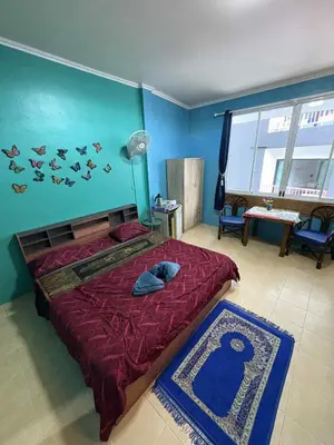 a bedroom with a large bed with a red comforter at San Antonio Beach Guesthouse & Restaurant in Kata Beach