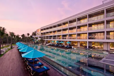 a hotel with chairs and umbrellas next to a swimming pool at Le Coral Resort in Natai Beach