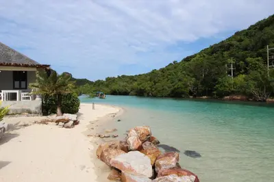 a beach with rocks in the water next to a house at Phi Phi Ba Kao Bay Resort in Phi Phi Don