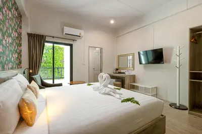 a bedroom with a large white bed with a statue on it at Ang Pao Hotel Phuket in Phuket Town