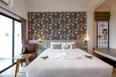 a bedroom with a large bed with a painting on the wall at Ang Pao Hotel Phuket in Phuket Town