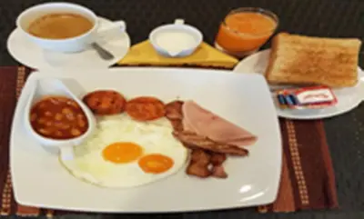 a plate of breakfast food with eggs sausage beans and coffee at Palmview Resort in Patong Beach