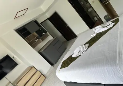 a bedroom with a white bed and a television at Beverly Hills Villa Patong in Patong Beach