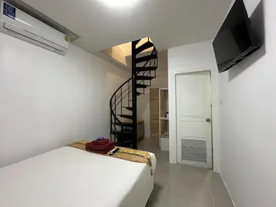a bedroom with a bed and a spiral staircase at Inn Dulgence in Patong Beach