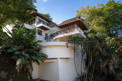a white house with a balcony and trees at Heavenly Villas in Patong Beach