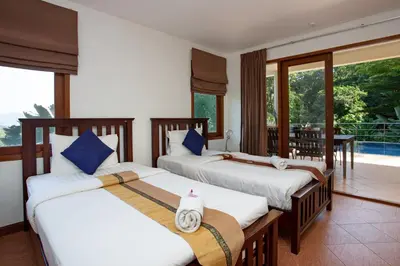 a bedroom with three beds and a balcony at Heavenly Villas in Patong Beach