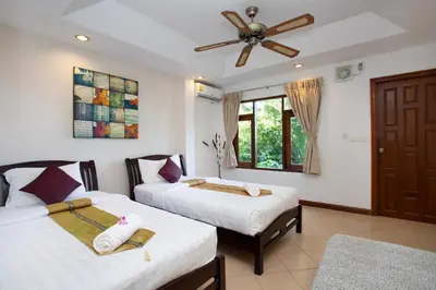 a bedroom with two beds and a ceiling fan at Heavenly Villas in Patong Beach