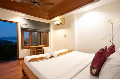 a bedroom with a bed and a window with a view at Heavenly Villas in Patong Beach