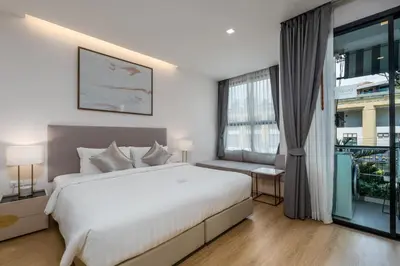 a bedroom with a large white bed and a window at The Proud Rawai Resort in Rawai Beach