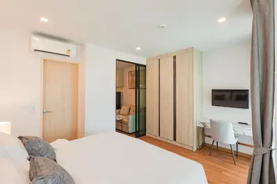 a bedroom with a bed and a desk and a tv at The Proud Rawai Resort in Rawai Beach